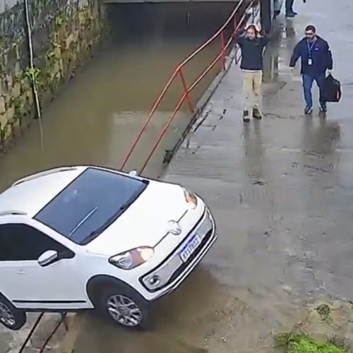 Carro sem motorista atravessa rua e cai em rio em Petrópolis; vídeo mostra reação de homem que leva as mãos à cabeça ao ver a situação